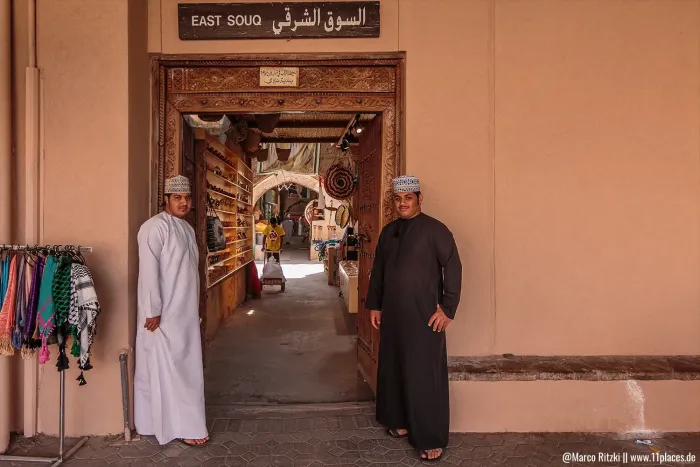 Eingang zum East Souq in Nizwa mit zwei omanischen Männern in traditioneller Kleidung