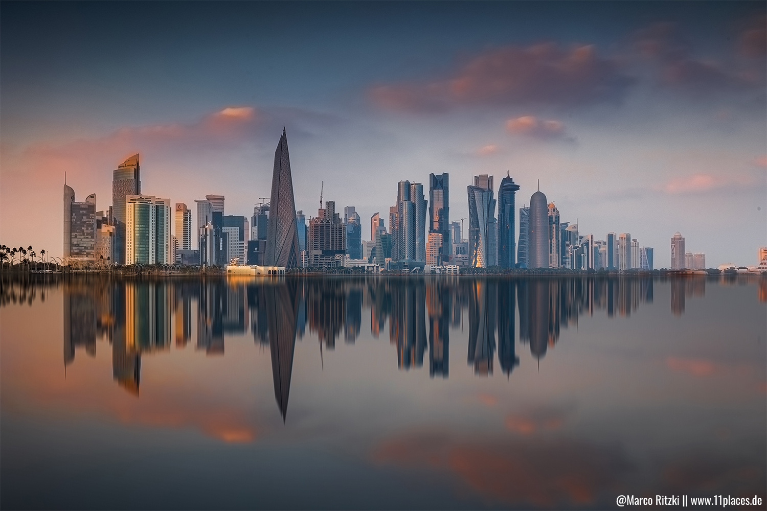 Skyline von Doha bei Sonnenuntergang mit Spiegelung im Wasser