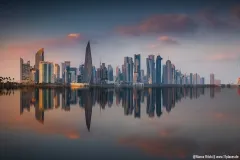 Skyline von Doha bei Sonnenuntergang mit Spiegelung im Wasser