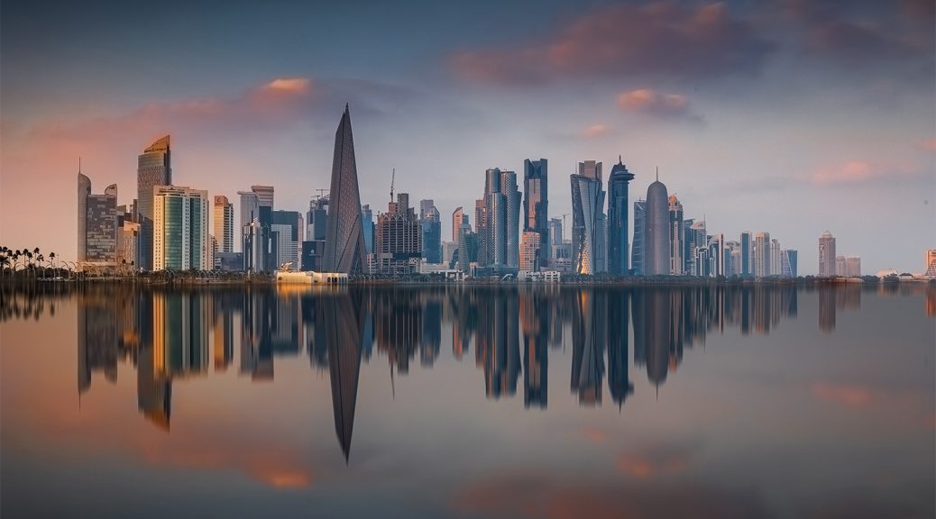 Skyline von Doha bei Sonnenuntergang mit Spiegelung im Wasser