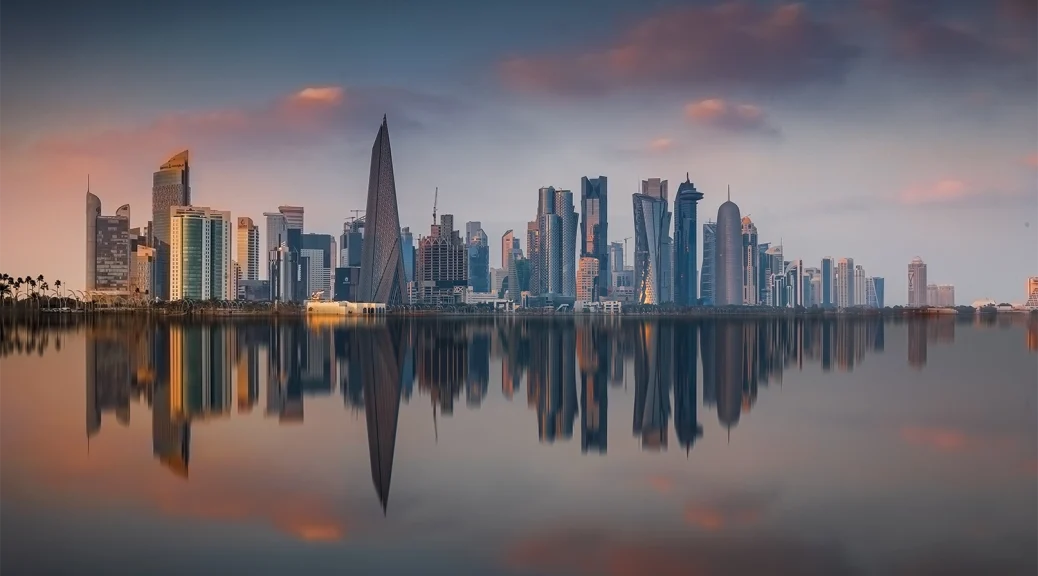 Skyline von Doha bei Sonnenuntergang mit Spiegelung im Wasser